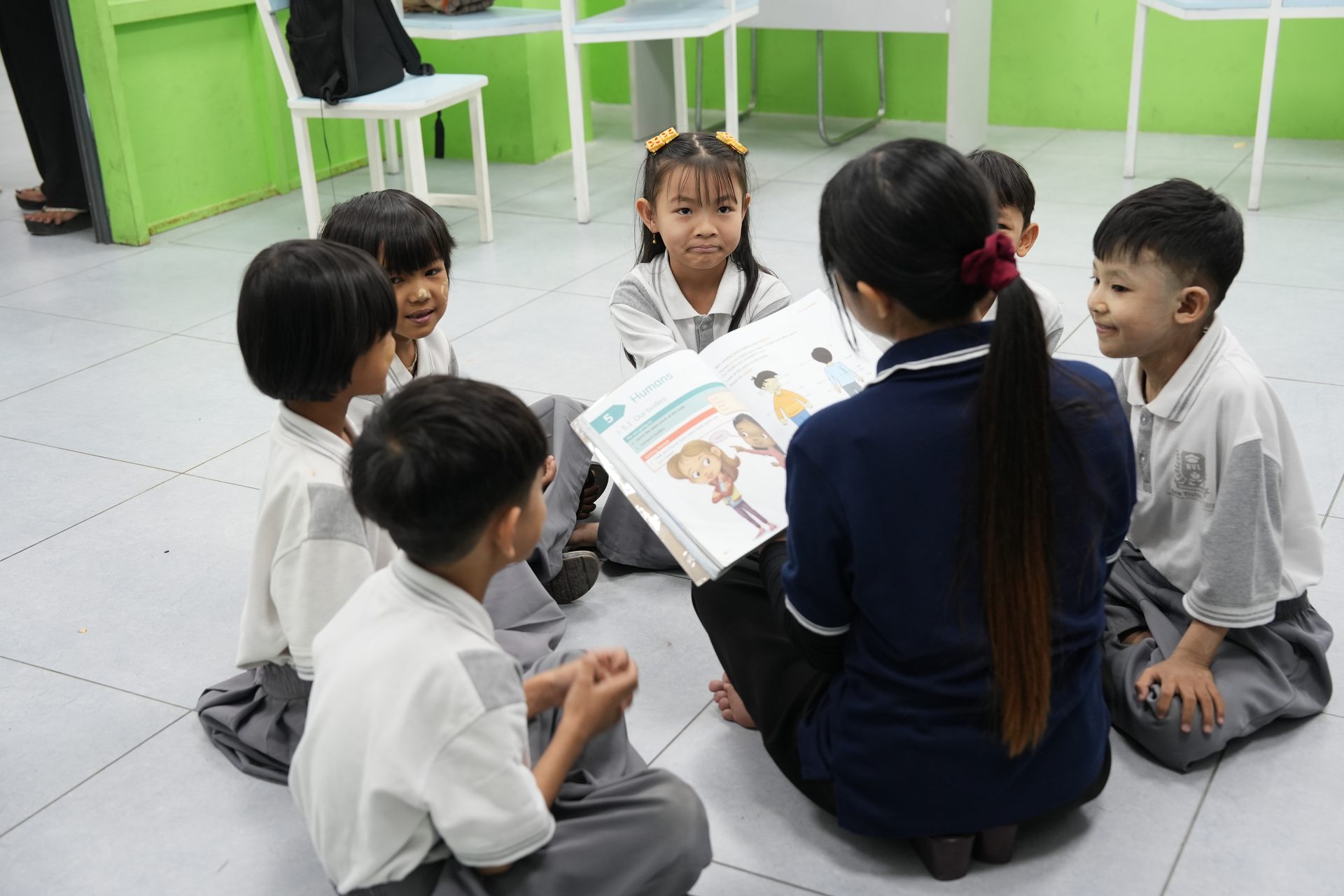 Primary learners collaborating with a teacher and learning material